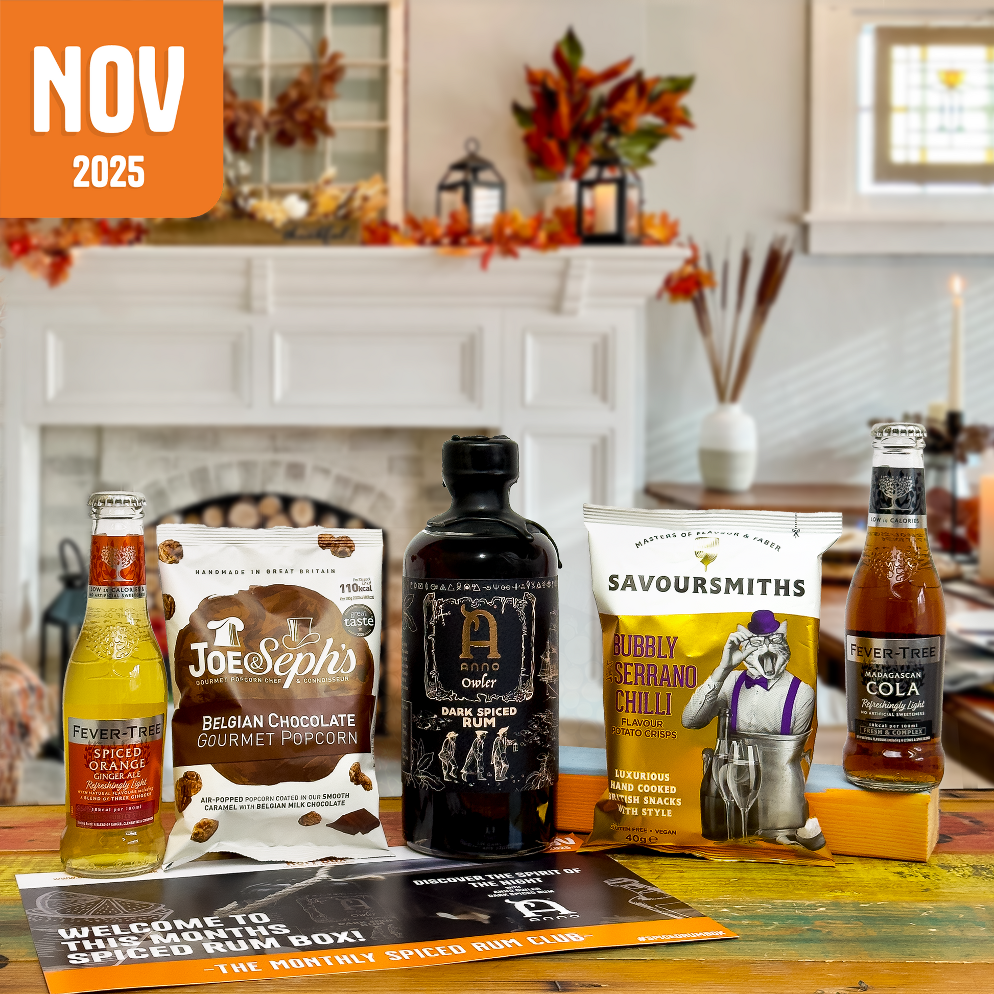 Assorted drinks and snacks on a table with a fireplace and autumn decorations in the background, featuring products from Joe Seph's, Savoursmiths, and Fever-Tree.